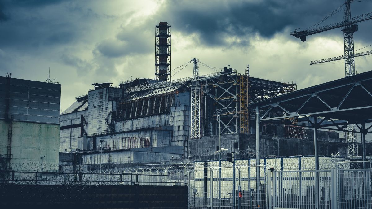 A csernobili atomerőmű romos épülete, sötét felhőkkel a háttérben.