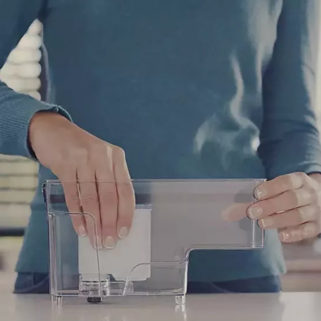 Egy nő kezében egy átlátszó víztartály, amelyet éppen tölt.