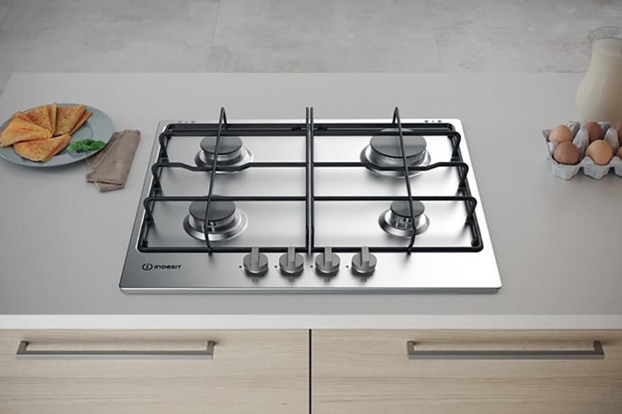 Modern Indesit gáztűzhely, mellette tányér sült palacsintával és tojásos doboz.